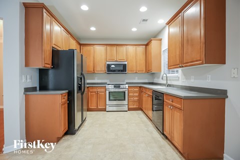 A kitchen with wooden cabinets and a black refrigerator.