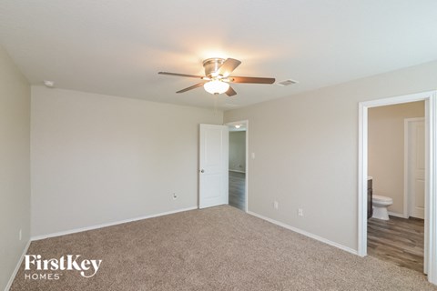 a spacious living room with carpet and a ceiling fan