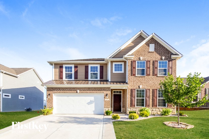 A two-story house with a garage and a tree in front.