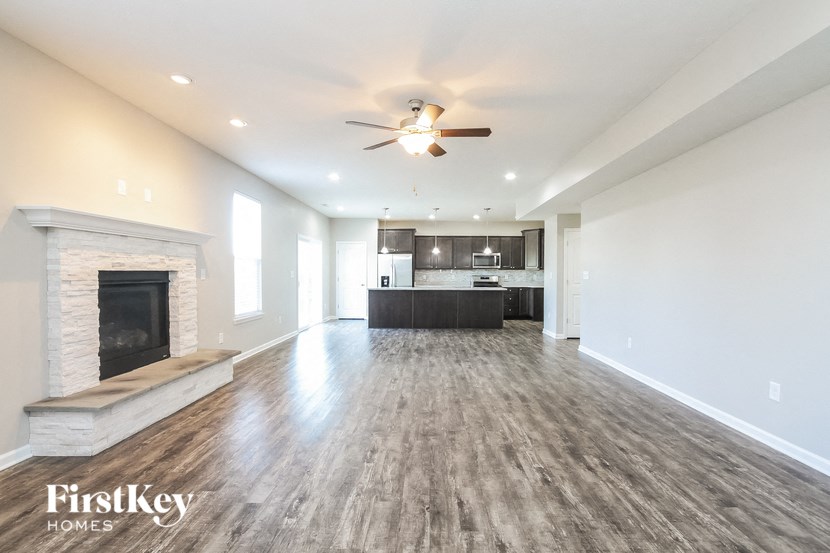 A spacious living room with a fireplace and a ceiling fan.