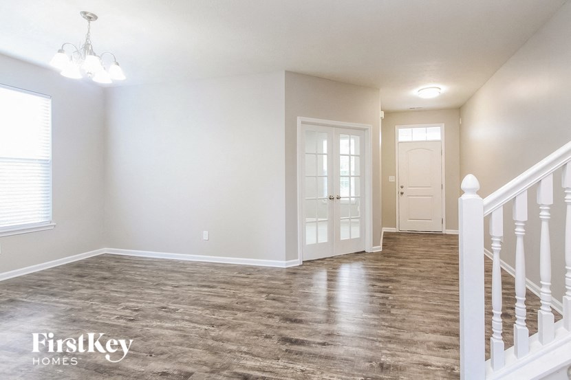 A spacious room with wooden flooring and white walls.