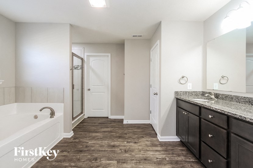 A bathroom with a tub, sink, and mirror.