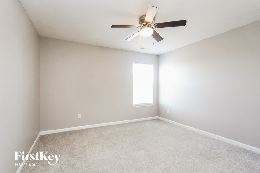 A room with a ceiling fan and a window letting in light.