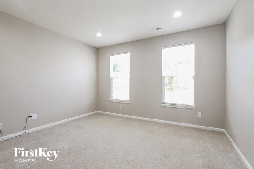 A room with two windows and a carpeted floor.