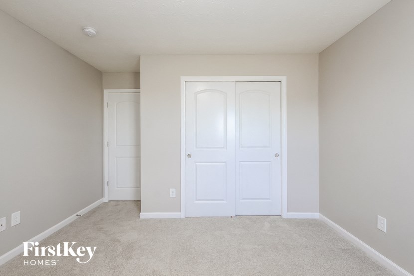A room with a white door and a carpeted floor.