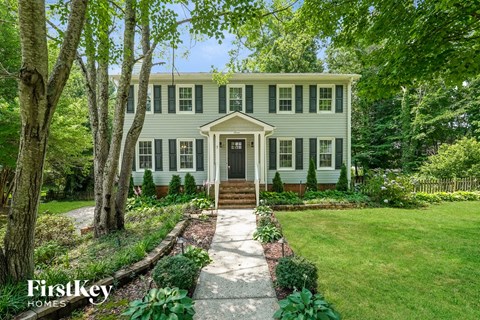 A house with a green lawn and trees in front of it.
