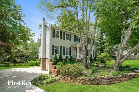 A house with a white picket fence and a brick pillar in front.