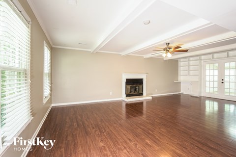 A spacious room with a fireplace and wooden floors.