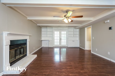 A spacious room with a fireplace and wood flooring.