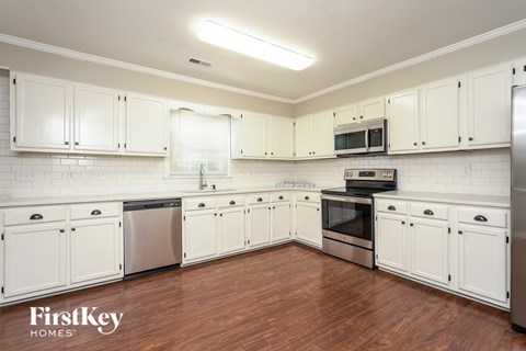 A kitchen with white cabinets and a wooden floor.