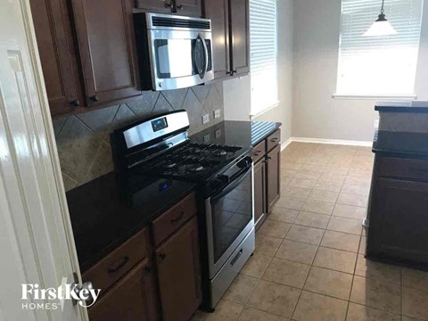 A kitchen with a black stove top oven and a microwave above it.
