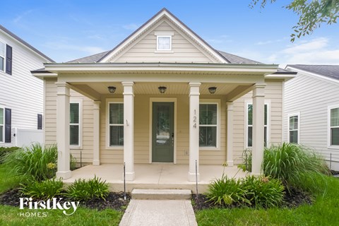 the front of a white house with white columns and a green door