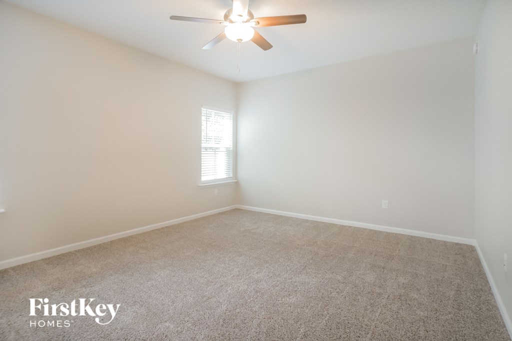 an empty room with a ceiling fan and a window