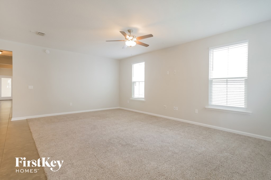 an empty living room with a ceiling fan and window
