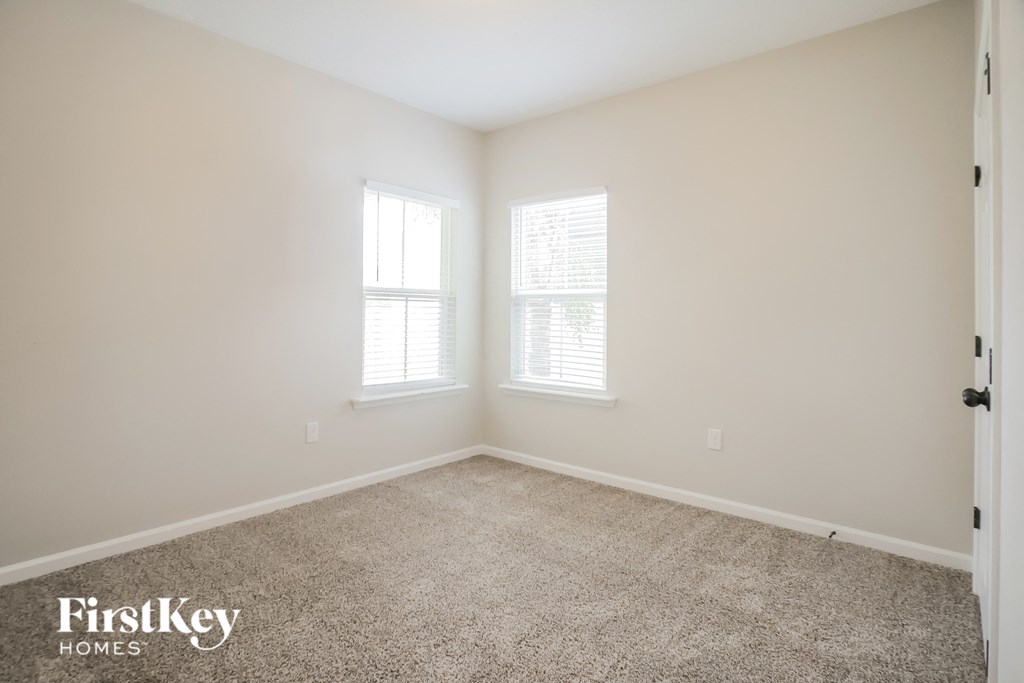 a empty room with carpet and two windows
