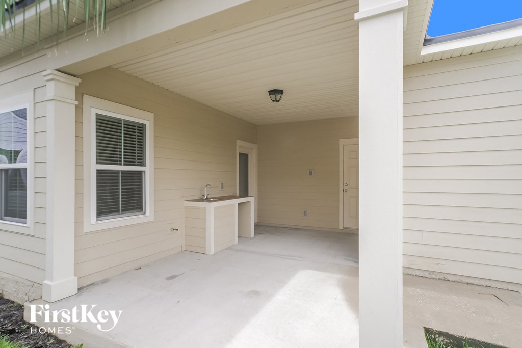 a covered porch in a home with white siding and a white door