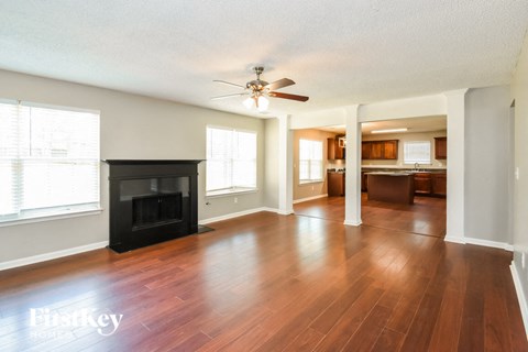 an empty living room with a fireplace and a ceiling fan