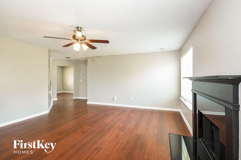 the living room and dining room with wood flooring and a ceiling fan