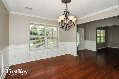 an empty dining room with a large window and a chandelier