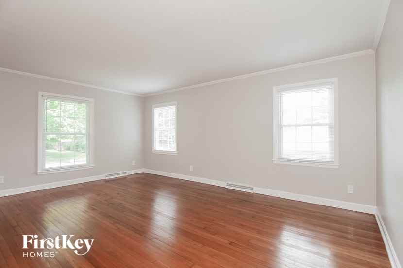 an empty room with wood floors and two windows