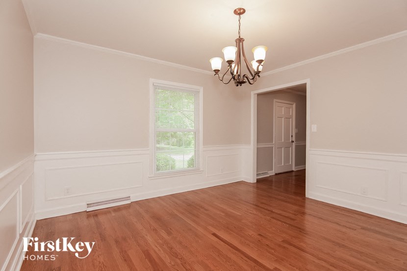 a dining room with white walls and wooden floors and a chandelier