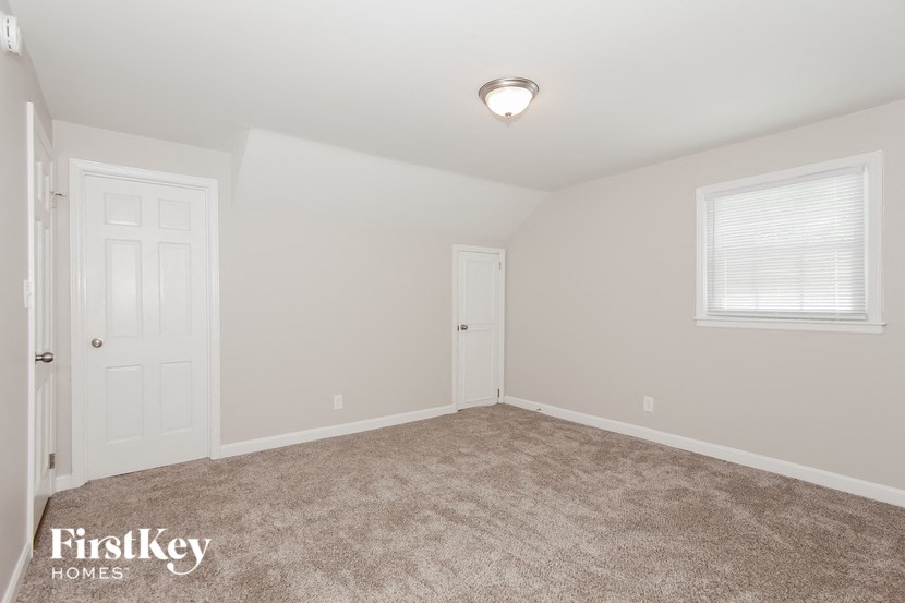 a bedroom with a carpeted floor and a white door and window