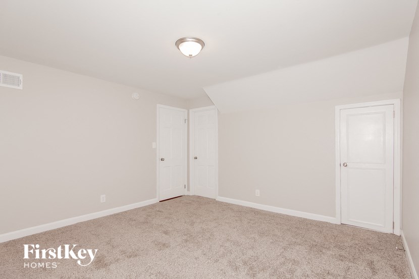 a bedroom with white walls and carpet and two doors