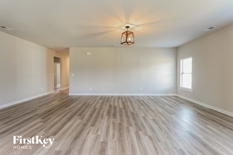 A room with wooden flooring and a light fixture hanging from the ceiling.