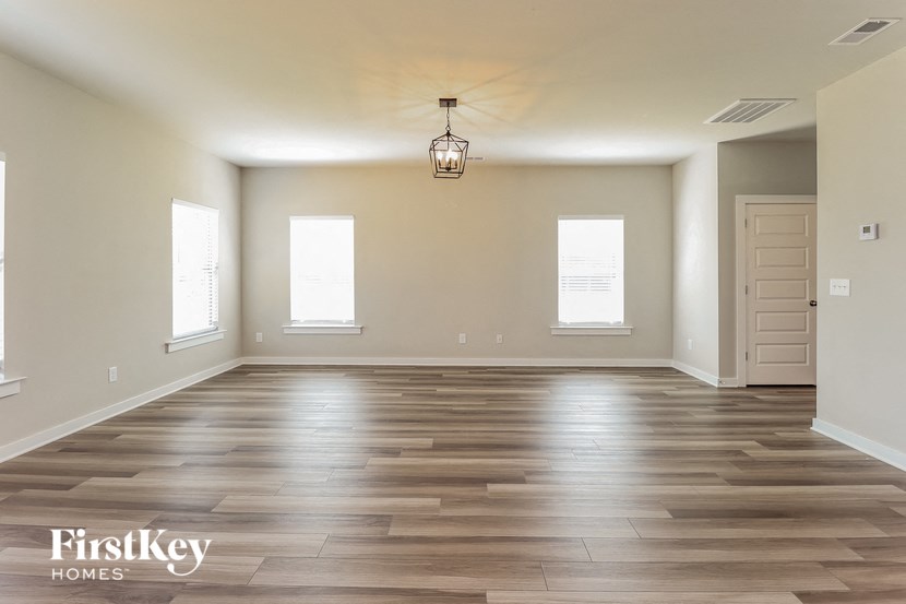 an empty living room with wood floors and a light fixture