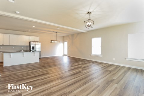 an empty living room and kitchen with wood flooring
