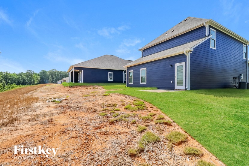 a blue house with green grass and a dirt driveway