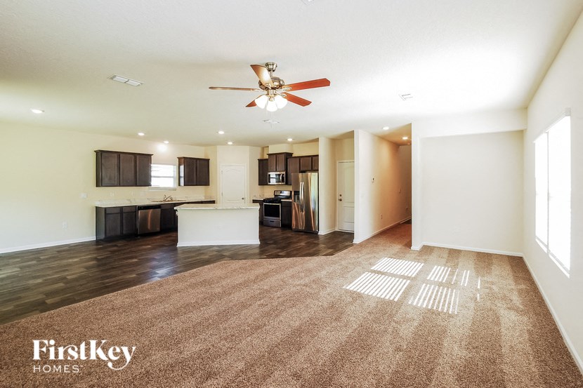 A spacious room with a carpeted floor and a ceiling fan.