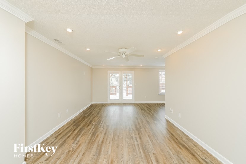 an empty living room with wood floors and a ceiling fan