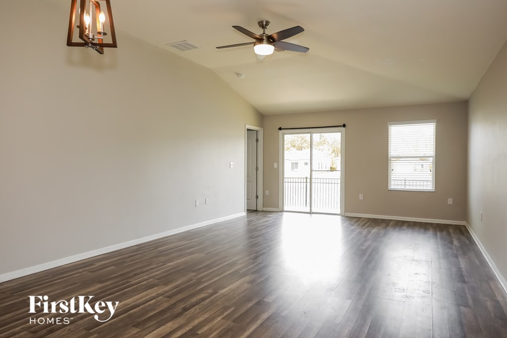 A spacious room with wooden floors and a ceiling fan.