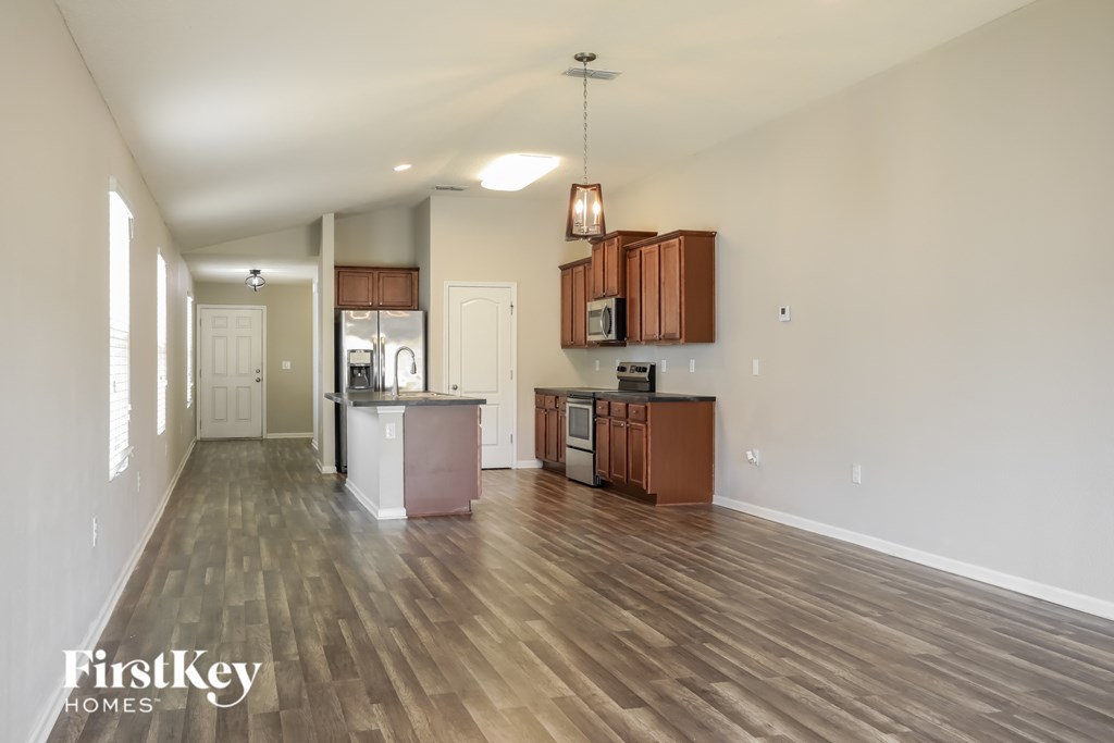 A spacious kitchen with wooden floors and a white refrigerator.