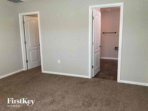 a bedroom with a carpeted floor and a door to a closet