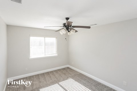 a bedroom with white walls and a ceiling fan