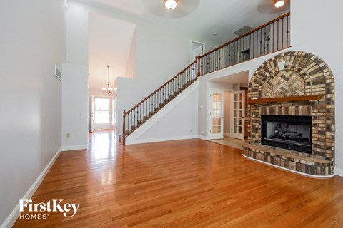 A large open living room with a stone fireplace and a staircase.