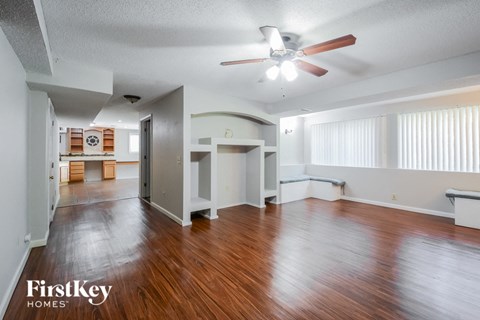 A spacious room with wooden floors and a ceiling fan.