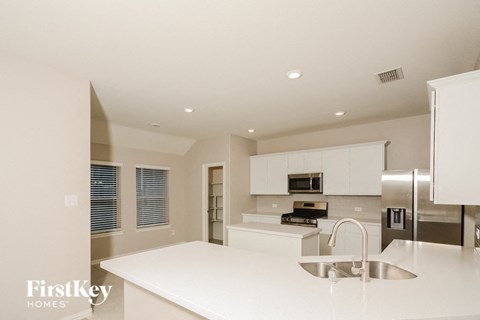 a white kitchen with stainless steel appliances and white counter tops