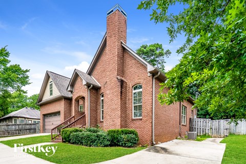 A brick house with a chimney and a fence in front.