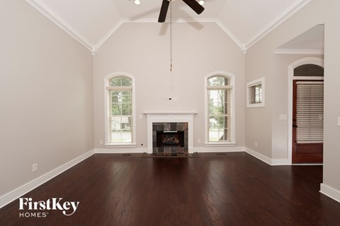 A spacious room with a fireplace and a ceiling fan.