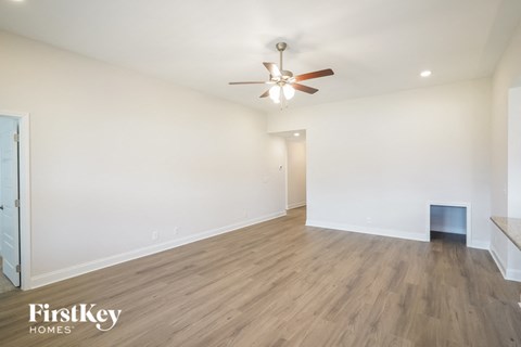 a living room with white walls and a ceiling fan