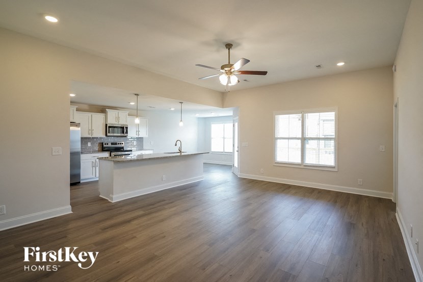 an empty living room and kitchen with a ceiling fan