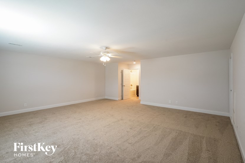 a spacious living room with carpeting and a ceiling fan