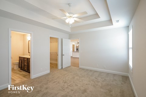 a spacious living room with carpet and a ceiling fan
