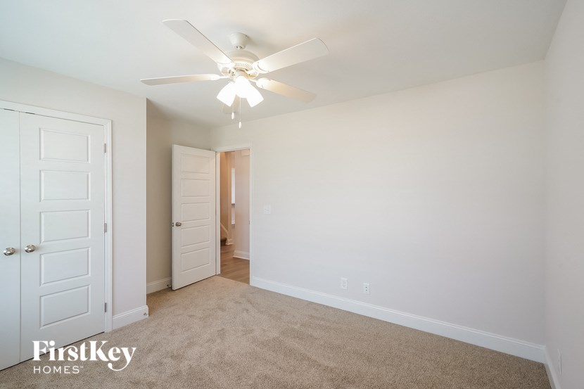 a bedroom with a ceiling fan and a door to a closet