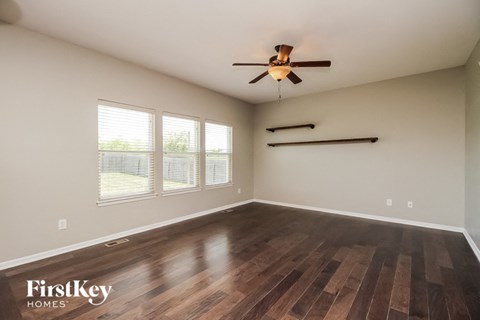 the living room with wood flooring and a ceiling fan