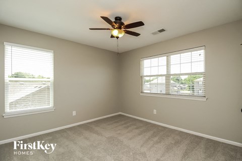 a bedroom with a ceiling fan and two windows