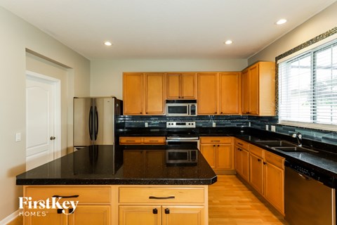 A kitchen with wooden cabinets and black countertops.